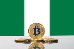 Goldene Bitcoins vor der grün-weißen Flagge des Landes Nigeria