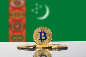 Goldener Bitcoin, eine Kryptowährung, drapiert vor der Flagge des Landes Turkmenistan