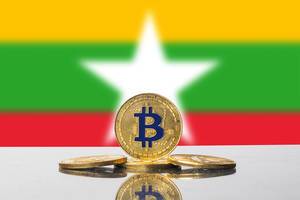 Goldener Bitcoin steht aufrecht vor dem weißem Stern der Flagge von Myanmar, dem früheren Burma