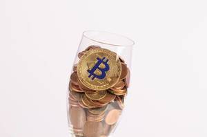 Goldener Bitcoin und Münzen im Champagner-Glas