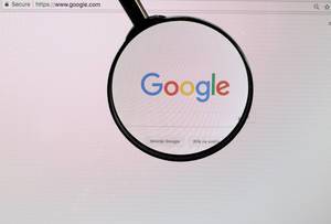 Google-Logo am PC-Monitor, durch eine Lupe fotografiert