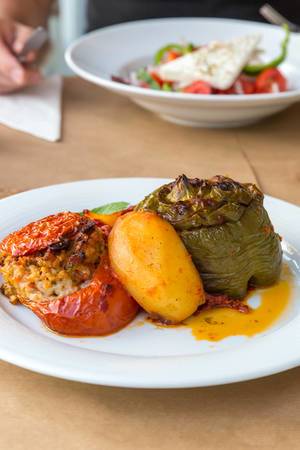 Greek dish called "Gemista", with red and green stuffed peppers, rice, pine nuts, raisins, mint leaves, fruits and yellow sauce