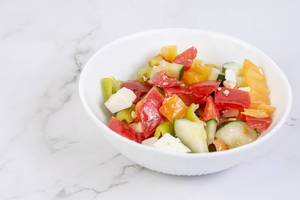 Greek Salad in the bowl above grey marble table