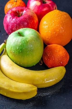 Green and red apples, bananas, oranges and tangerines with water drops