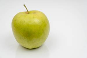 Green Apple on the white reflective surface with copy space (Flip 2020)