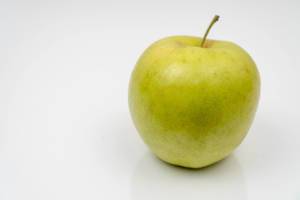 Green Apple on the white reflective surface with copy space