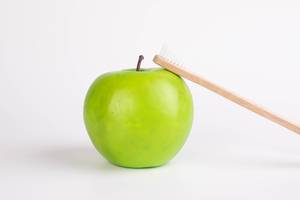 Green apple with wooden toothbrush