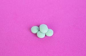 Green pills on pink background