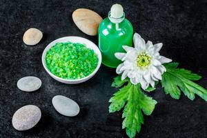 Green salt and gel for Spa treatments with sea stones on a black background