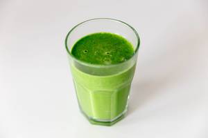 Green Smoothie drink in a glass on a white table