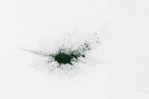 Green spirulina powder spread over a white table