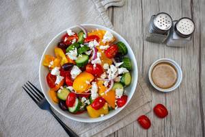 Griechischer Salat mit Cherrytomaten, Paprika, Gurke, Zwiebel, schwarzen Oliven und Fetakäse. Draufsicht