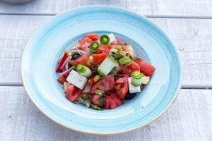 Griechischer Salat mit Tomate, Gurke, Zwiebel, sonnengetrocknete Tomate, Fetakäse, Kapern und Olivenöl