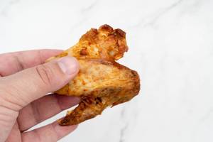 Grilled Chicken Wings in the hand above white background