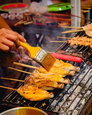 Grillmeister bestreicht mit einem Pinsel das Hähnchenfleisch für das Barbecue mit Öl