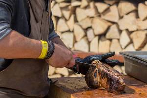 Grillmeister von OFYR trennt Knochen mit Fleischmesser von saftig gegrillten Lammkoteletts