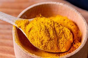 Ground turmeric in a wooden spoon