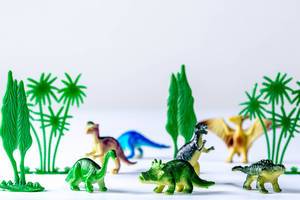 Group of toy plastic dinosaurs over white