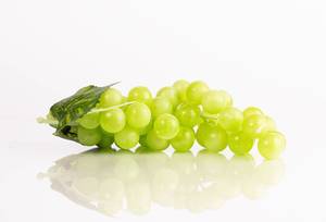 Grüne Weintrauben mit Blättern, isoliert vor weißem Hintergrund