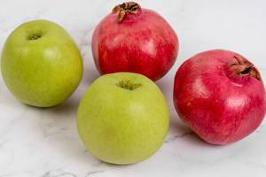 Grüner Apfel und Granatapfel auf Marmoroberfläche