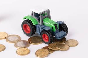 Grüner Traktor mit Euro-Münzen vor weißem Hintergrund