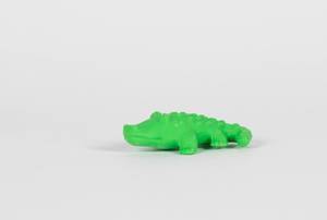 Grünes Spielzeug-Krokodil vor weißem Hintergrund