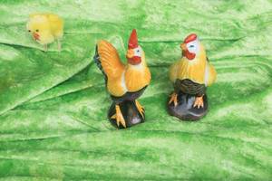 Hahn und Huhn aus Porzellan auf einem grünen Tuch