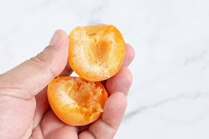 Halbierte Aprikosenscheiben in einer Hand