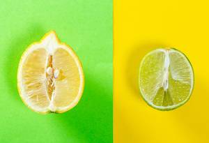 Half a lemon on a green background and half a lime on a yellow won