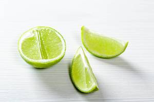 Half and pieces of ripe lime on white background
