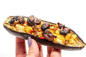 Half eggplant with mushrooms, vegetables and couscous in a woman
