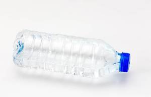 Half empty plastic water bottle with no label and blue cap