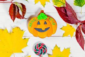 Halloween gingerbread pumpkin with autumn leaves and candy