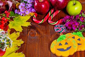 Halloween gingerbread pumpkin with autumn leaves, flowers, apples and candy