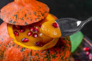 Halloween treats concept-pumpkin with pumpkin puree and pomegranate with spoon closeup (Flip 2019)