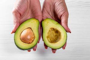 Halves of ripe avocado in the hands of a woman