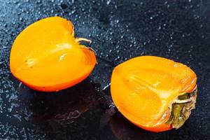 Halves of ripe persimmon with drops