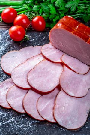 Ham with vegetables and greens on a dark background