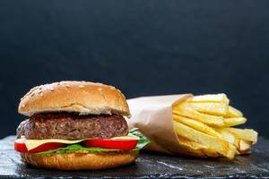 Hamburger und frische Pommers vor schwarzem Hintergrund