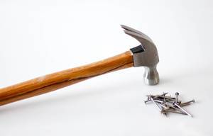 Hammer laying next to a bunch of nails on white background