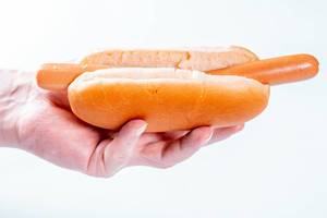 Hand eines Mannes hält Hotdog ohne Soße oder weitere Zutaten vor weißem Hintergrund