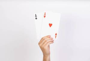 Hand hält die höchsten Spielkarten mit zwei Asse, vor weißem Hintergrund