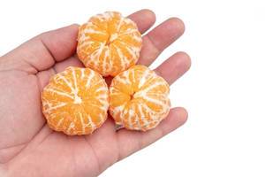 Hand hält drei geschälte Mandarinen