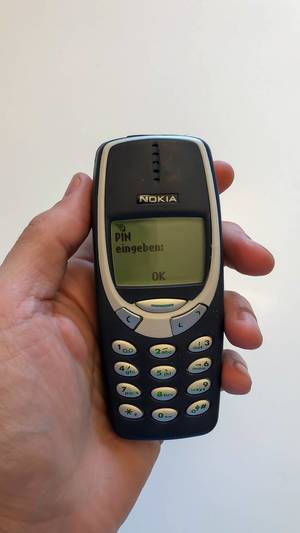 Hand hält ein klassisches Nokia 3310 Handy vor weißem Hintergrund