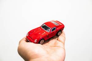 Hand hält ein kleines rotes Auto