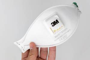 Hand hält eine Aura FFP3 Atemschutzmaske 9332+ von 3M vor weißem Hintergrund