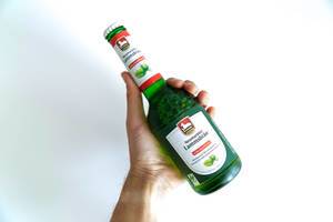 Hand hält eine Bierflasche mit alkoholfreiem Bio-Neumarkter Lammsbräu vor einen weißen Hintergrund