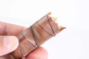 Hand hält einen angebissenen Schokoladenriegel