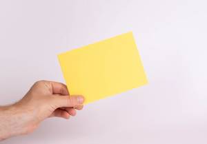 Hand hält einen gelben Umschlag vor weißem Hintergrund