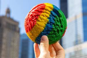 Hand hält einen kunterbunten Regenbogen-Cookie mit den Wolkenkratzern von Chicago im Hintergrund
